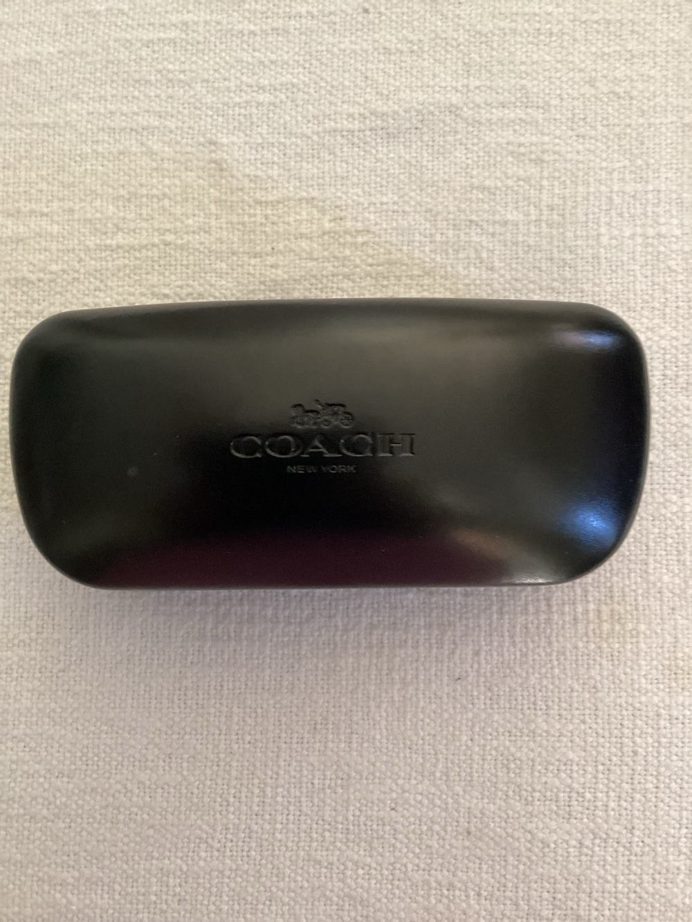 Black Coach New York branded hard-shell glasses case.